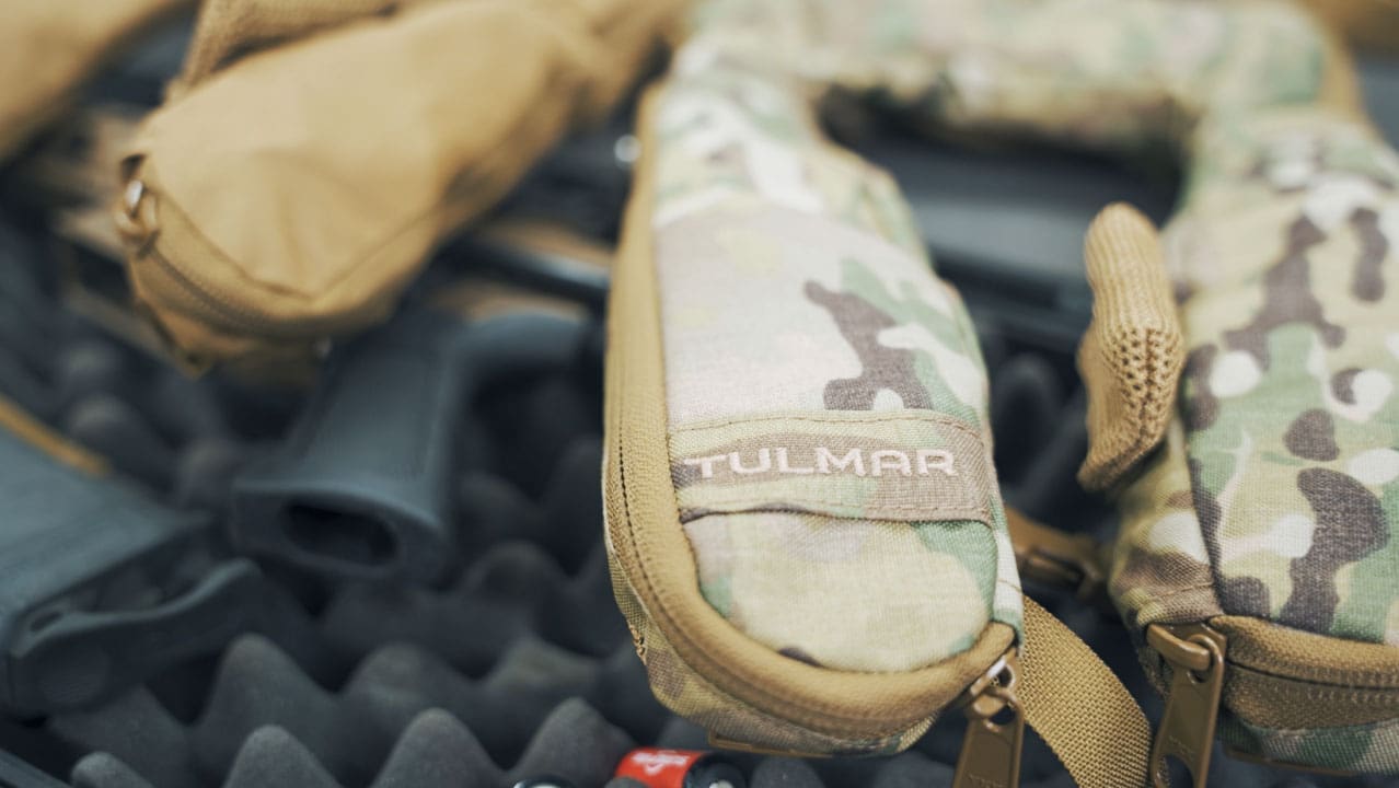 Camouflage military gear and firearm parts on a textured background.